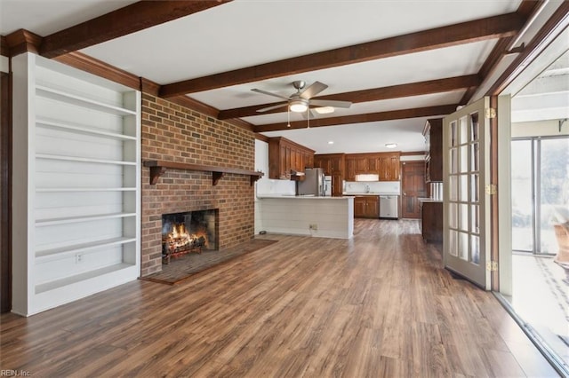 unfurnished living room with dark hardwood / wood-style flooring, beam ceiling, ceiling fan, and a fireplace