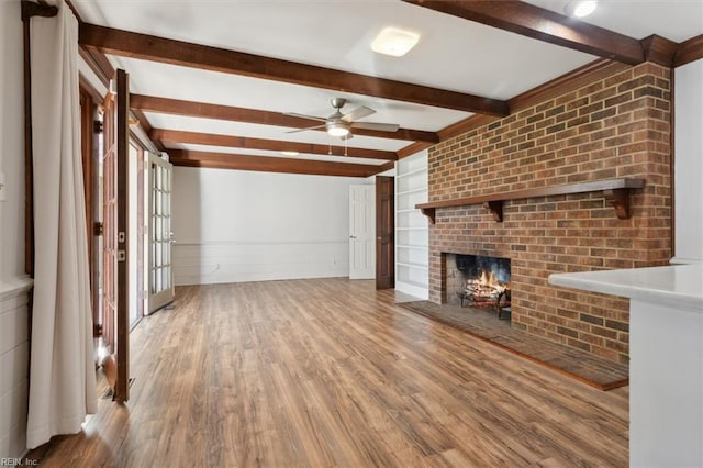 unfurnished living room with a fireplace, wood-type flooring, ceiling fan, and lofted ceiling with beams