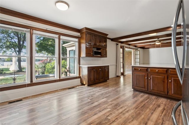 kitchen with ceiling fan, beam ceiling, and light hardwood / wood-style flooring