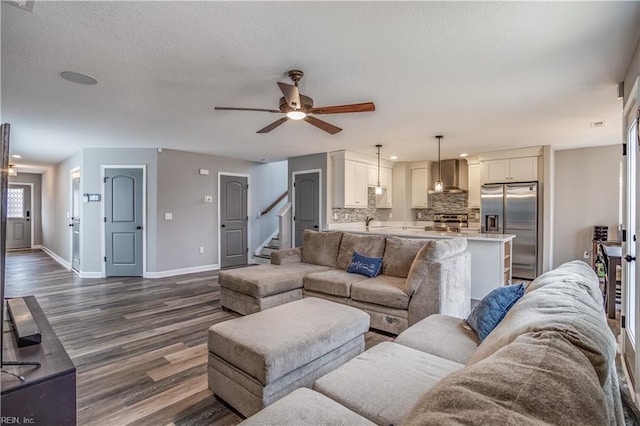 living room with a textured ceiling, dark hardwood / wood-style flooring, ceiling fan, and sink