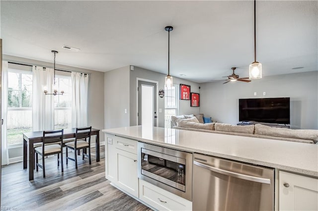 kitchen with decorative light fixtures, white cabinetry, appliances with stainless steel finishes, and light hardwood / wood-style floors