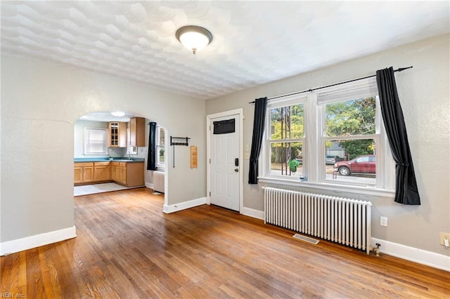 foyer featuring sink, radiator, and light hardwood / wood-style flooring