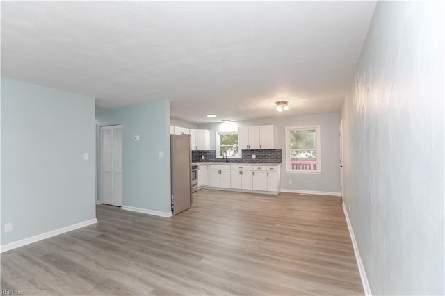 kitchen featuring white cabinets, light hardwood / wood-style floors, stainless steel appliances, and tasteful backsplash