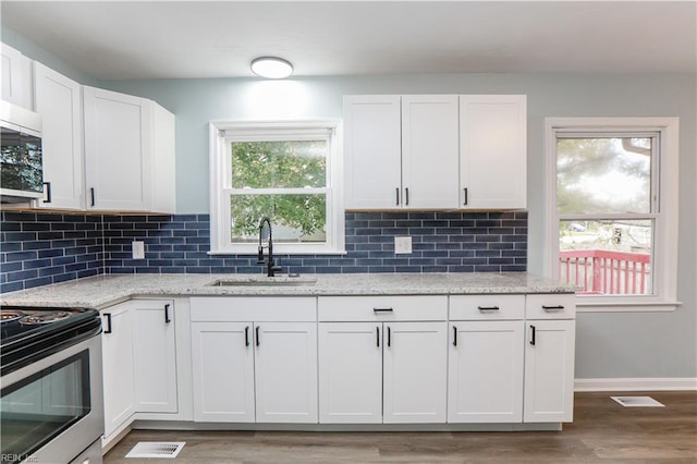 kitchen featuring white cabinetry, sink, appliances with stainless steel finishes, light stone counters, and hardwood / wood-style floors