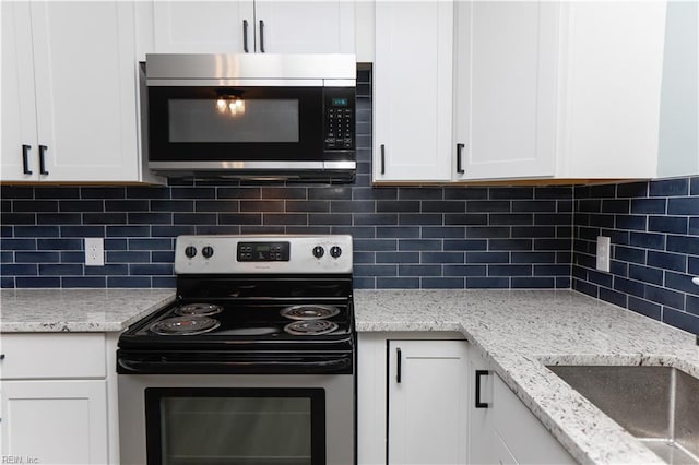 kitchen featuring white cabinetry, backsplash, light stone countertops, and stainless steel appliances