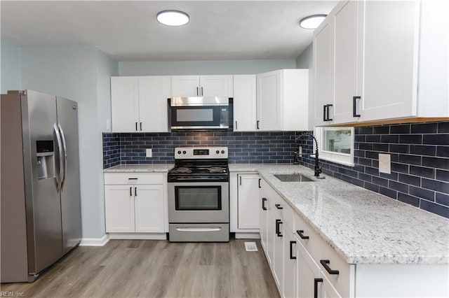 kitchen featuring white cabinets, light wood-type flooring, appliances with stainless steel finishes, and sink