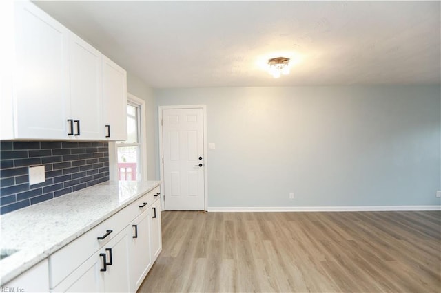 kitchen featuring white cabinets, light wood-type flooring, decorative backsplash, and light stone countertops