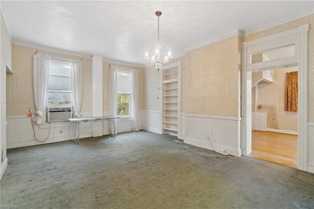 carpeted spare room featuring cooling unit, built in features, crown molding, and a chandelier