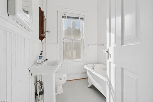 bathroom featuring toilet and a tub to relax in