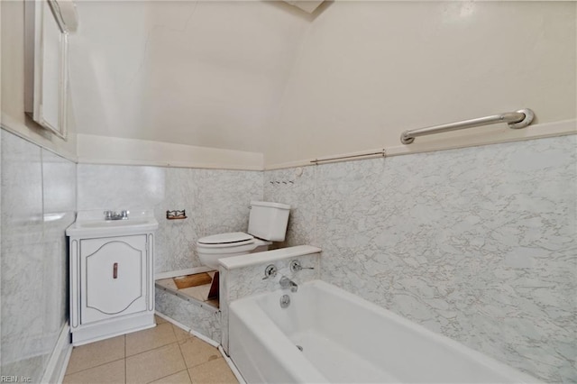 bathroom with a bath, sink, tile patterned flooring, toilet, and tile walls