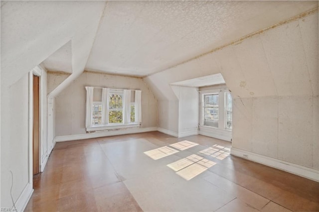 bonus room with plenty of natural light, lofted ceiling, and a textured ceiling