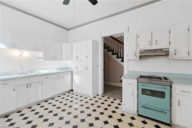 kitchen with decorative backsplash, ceiling fan, sink, white cabinets, and stainless steel stove