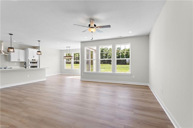 unfurnished living room with ceiling fan, light wood-type flooring, and sink