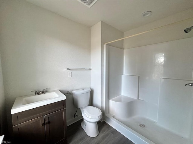 bathroom with walk in shower, wood-type flooring, vanity, and toilet