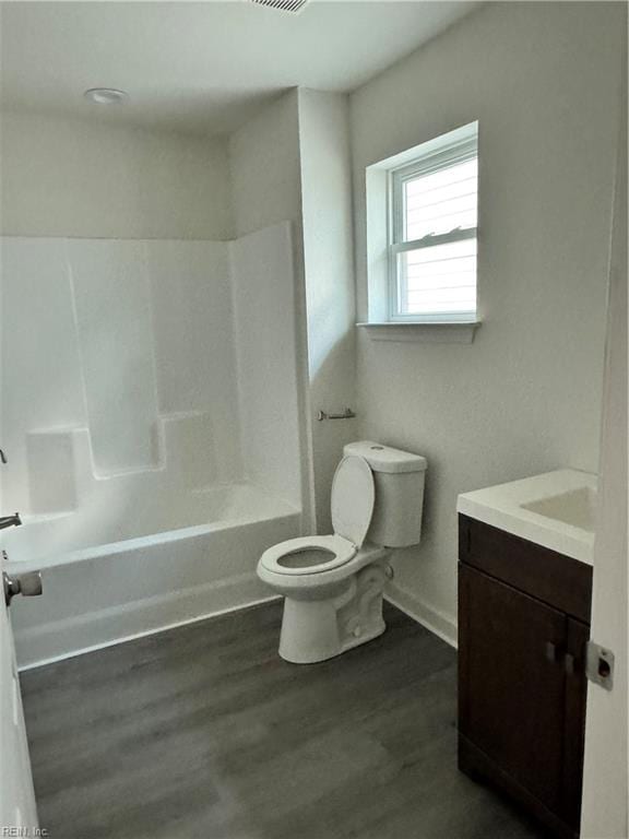 full bathroom featuring vanity, wood-type flooring, washtub / shower combination, and toilet