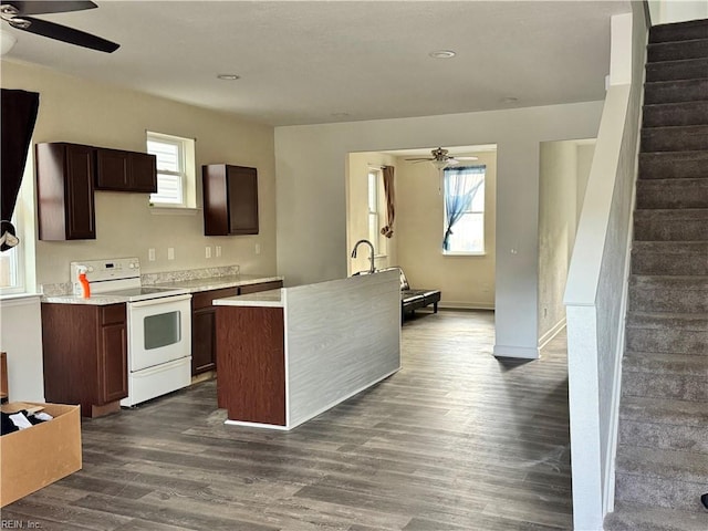 kitchen with electric stove, dark brown cabinets, dark hardwood / wood-style flooring, ceiling fan, and a center island