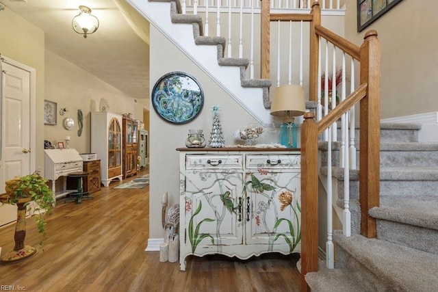 stairway featuring wood-type flooring and vaulted ceiling