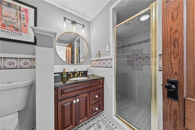 bathroom with walk in shower, vanity, tile patterned floors, toilet, and tile walls