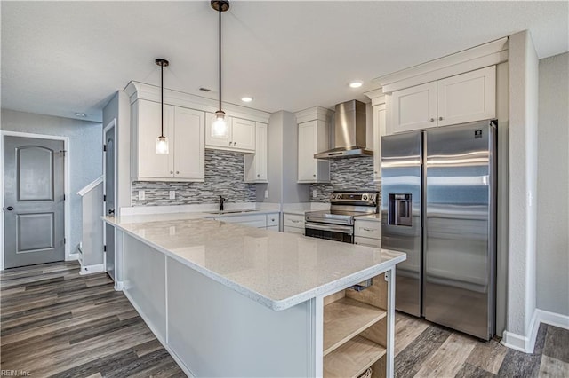 kitchen with appliances with stainless steel finishes, sink, wall chimney range hood, decorative light fixtures, and white cabinetry