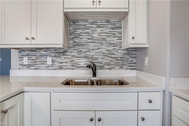 kitchen with white cabinets, decorative backsplash, sink, and light stone counters