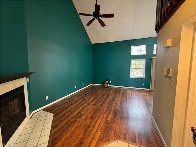 unfurnished living room with hardwood / wood-style floors, a fireplace, high vaulted ceiling, and ceiling fan