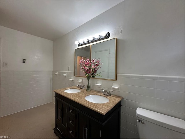 bathroom with a sink, wainscoting, toilet, and tile walls