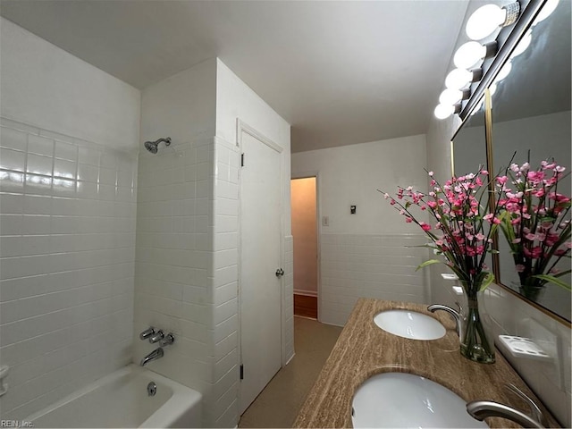 bathroom featuring a sink, tile walls, double vanity, and shower / washtub combination