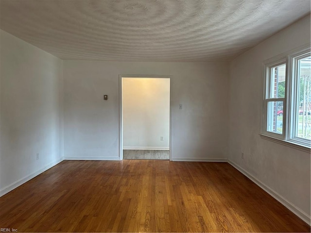 spare room with baseboards and wood finished floors