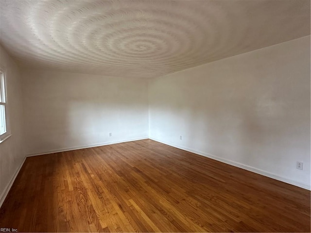 empty room with baseboards and wood finished floors