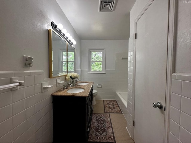 bathroom featuring visible vents, tile walls, tile patterned flooring, vanity, and toilet