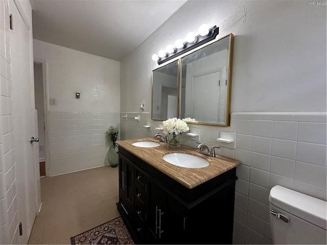 bathroom featuring a sink, tile walls, wainscoting, and toilet