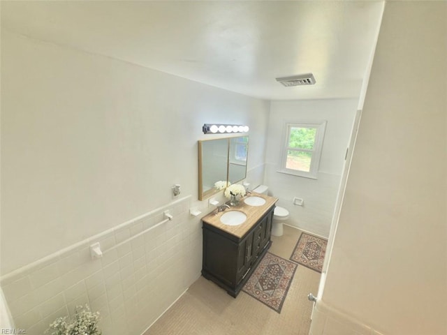 bathroom featuring tile patterned flooring, vanity, toilet, tile walls, and visible vents