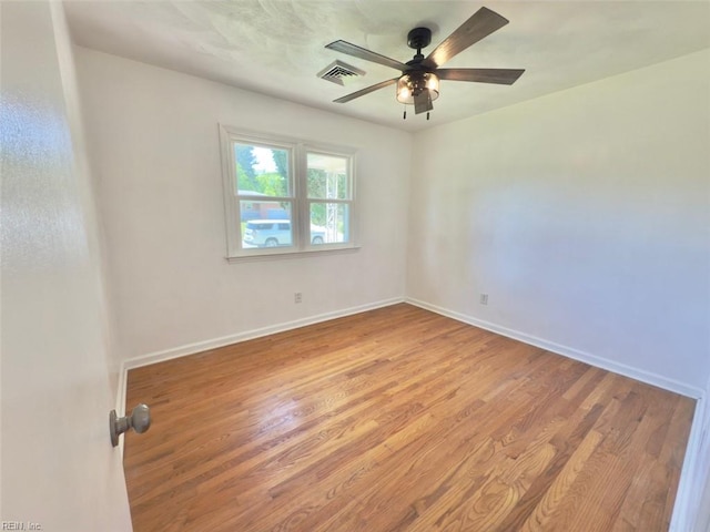 unfurnished room featuring a ceiling fan, baseboards, visible vents, and wood finished floors