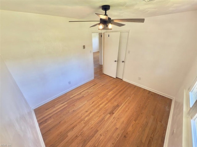 spare room featuring baseboards, light wood finished floors, and ceiling fan
