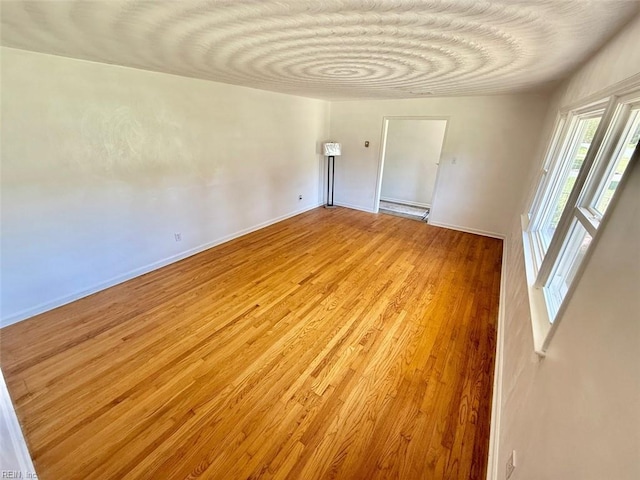 unfurnished room featuring baseboards and light wood-style flooring