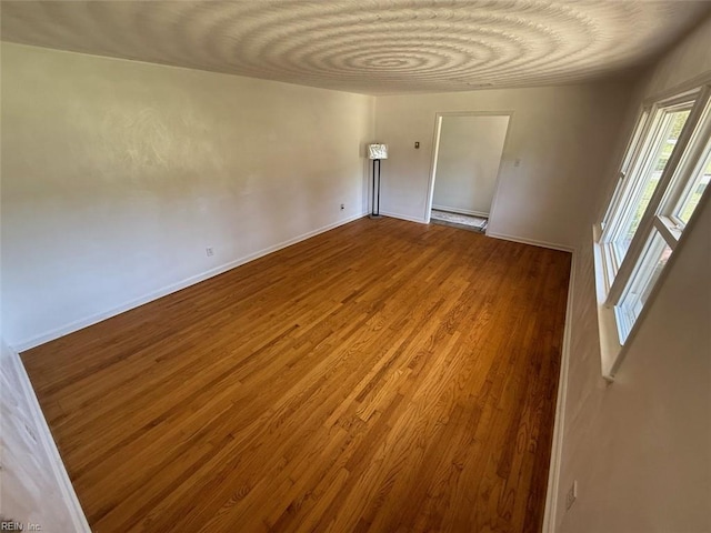unfurnished room featuring baseboards and wood finished floors