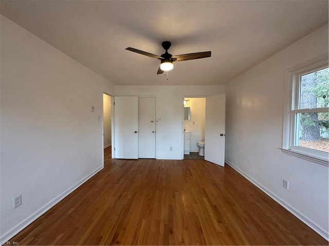 unfurnished bedroom featuring connected bathroom, baseboards, ceiling fan, and wood finished floors