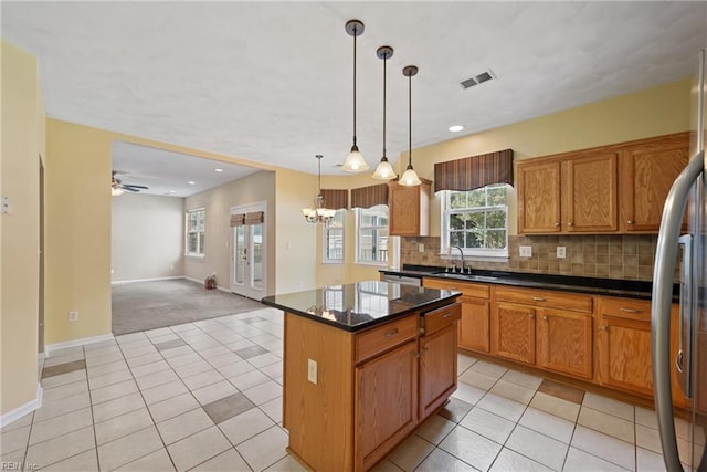 kitchen featuring backsplash, ceiling fan with notable chandelier, hanging light fixtures, light tile patterned floors, and a kitchen island