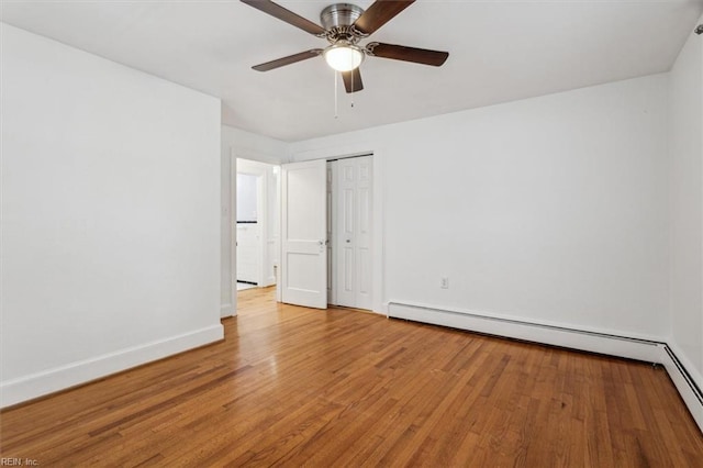 unfurnished room featuring hardwood / wood-style floors, ceiling fan, and a baseboard heating unit