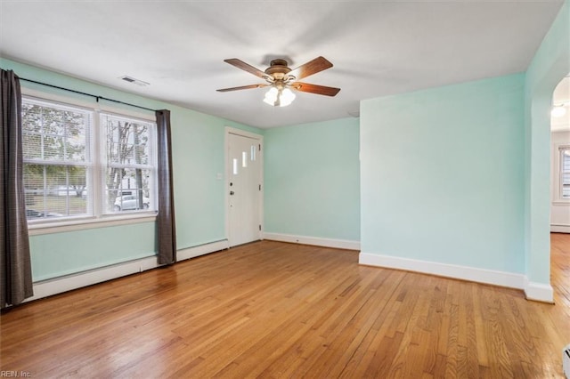 empty room featuring ceiling fan, light wood-type flooring, and baseboard heating