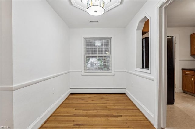 unfurnished dining area featuring a baseboard radiator and light wood-type flooring