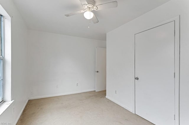 unfurnished bedroom with multiple windows, ceiling fan, and light colored carpet