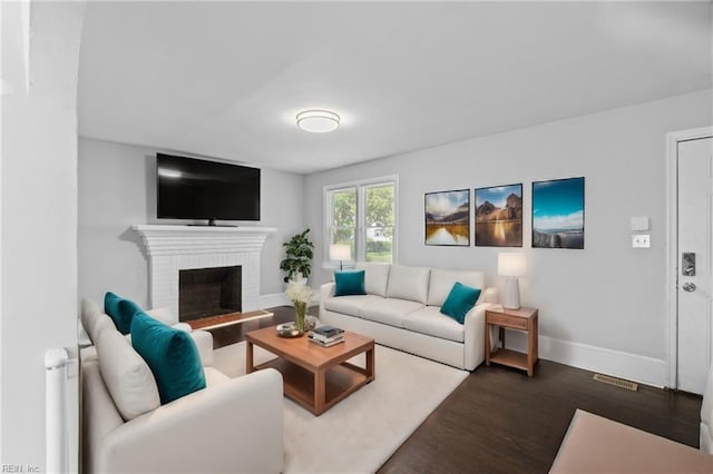 living room featuring dark hardwood / wood-style flooring and a brick fireplace