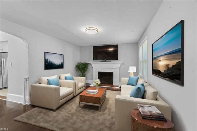 living room featuring wood-type flooring and a brick fireplace