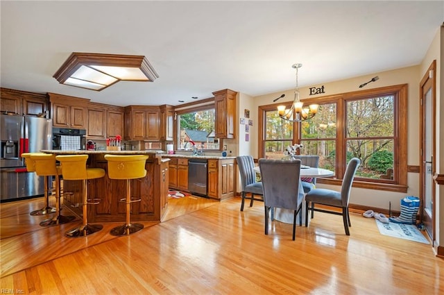 kitchen featuring plenty of natural light, light wood-type flooring, hanging light fixtures, and appliances with stainless steel finishes