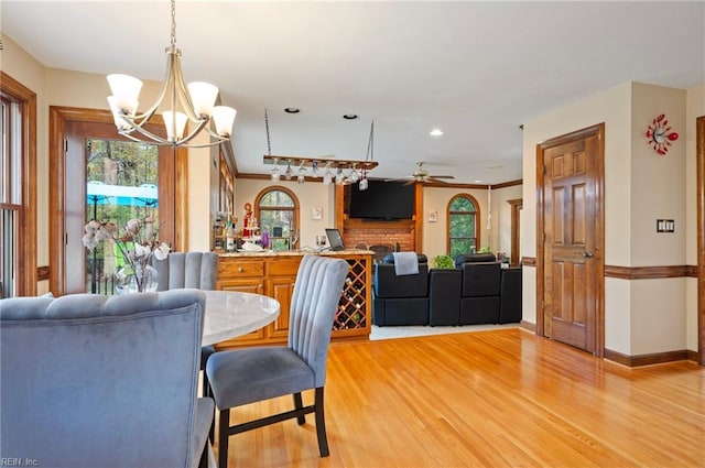 dining room with plenty of natural light, crown molding, light wood-type flooring, and ceiling fan with notable chandelier