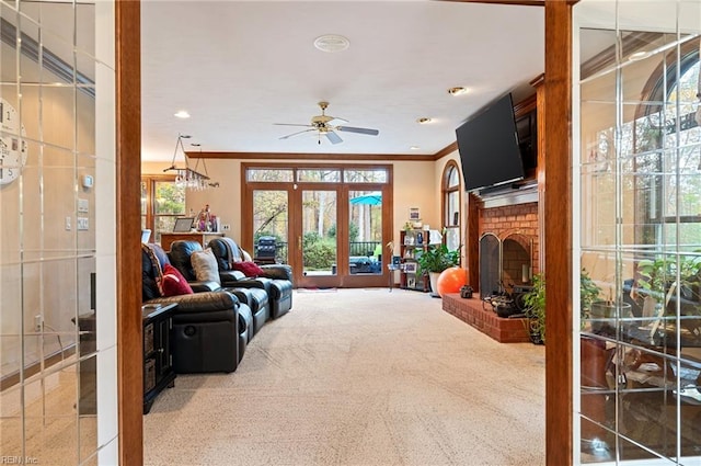 living room with french doors, a brick fireplace, ceiling fan, ornamental molding, and carpet floors