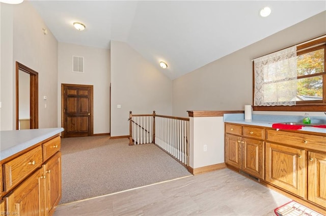 hallway with light carpet and vaulted ceiling