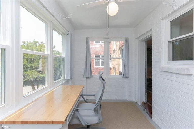 office space featuring brick wall, light wood-type flooring, plenty of natural light, and ceiling fan