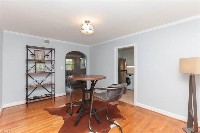 dining space featuring hardwood / wood-style floors, ornamental molding, and washer / clothes dryer